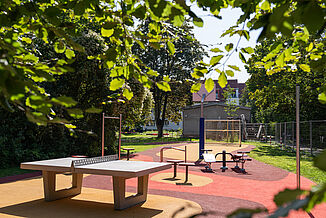 Barrierefreier Spielplatz in Berlin-Steglitz-Zehlendorf mit REGUPOL Fallschutzboden, Tischtennisplatte, Fitnessgeräten und inklusiver Spiel- und Bewegungsfläche für Kinder, Familien und Erwachsene.
