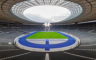 Olympiastadion Berlin mit leerem Innenraum und charakteristischer blauer Kunststofflaufbahn, bekannt als „das blaue Wunder“. Die moderne Leichtathletikanlage dient als Bühne für nationale und internationale Leichtathletikwettkämpfe.