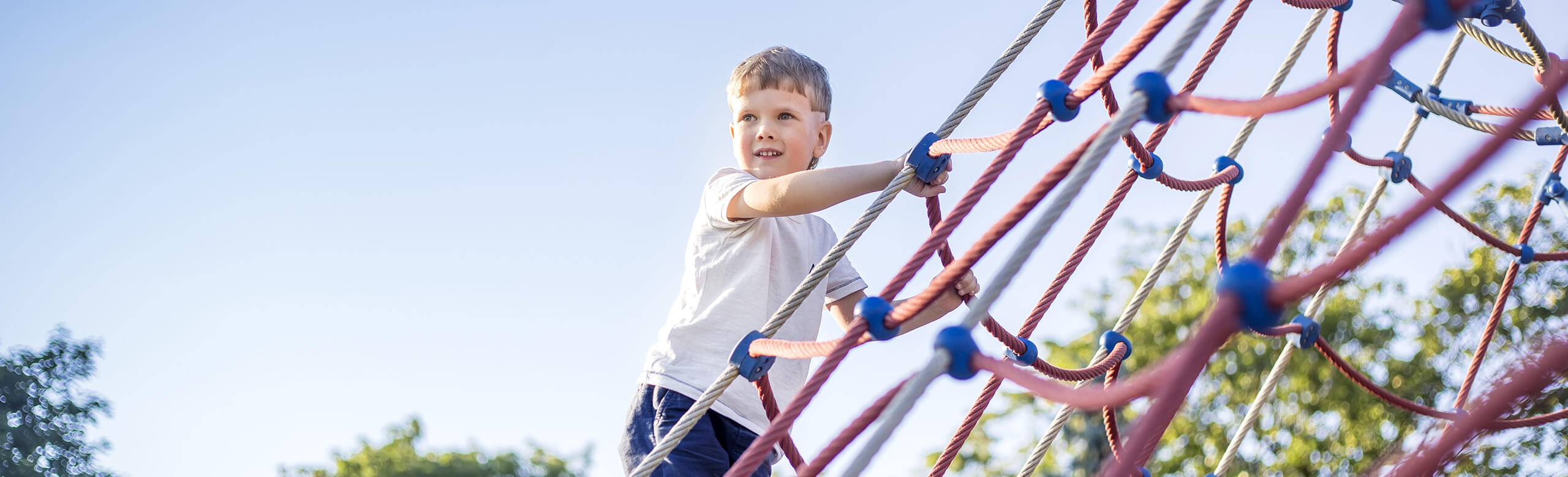 Kind klettert auf Spielplatz mit REGUPOL Fallschutzböden