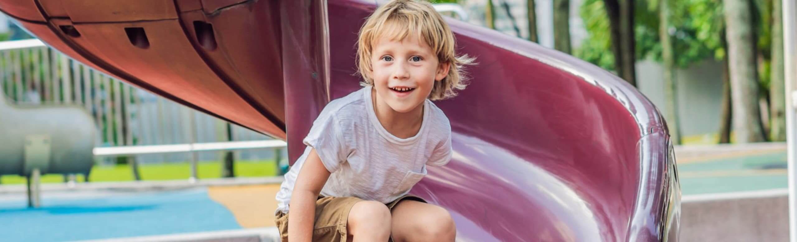 Kind spielt auf einer Rutsche auf einem Spielplatz mit fugenlosem REGUPOL Fallschutz