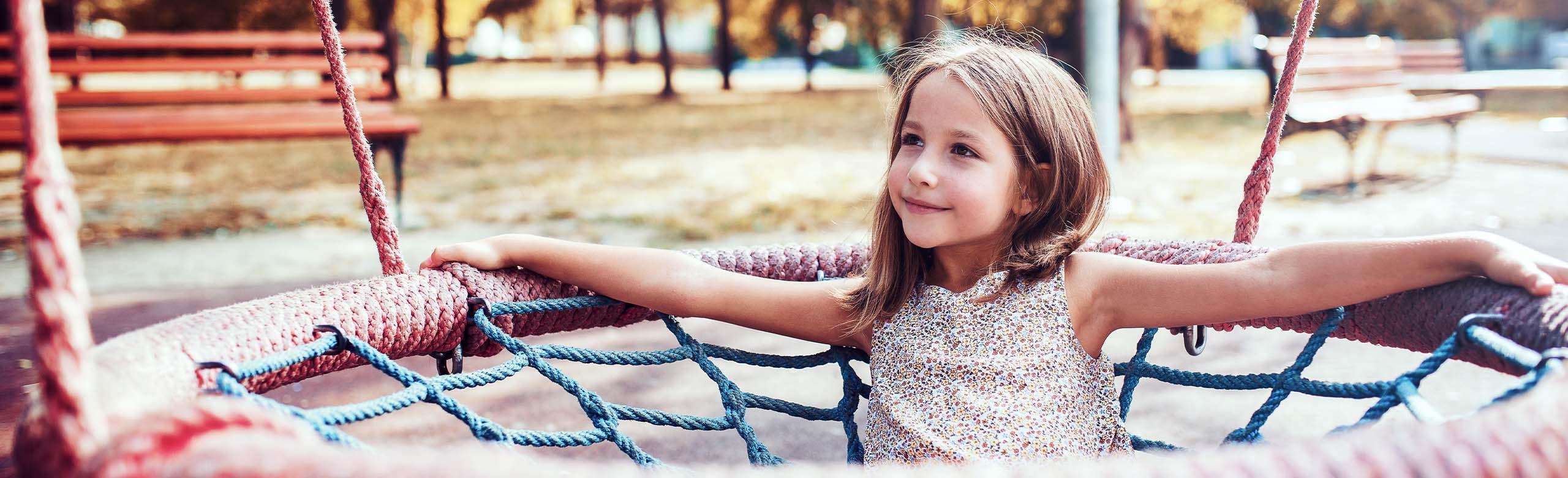 A child playing happily on a playground with REGUPOL safety flooring